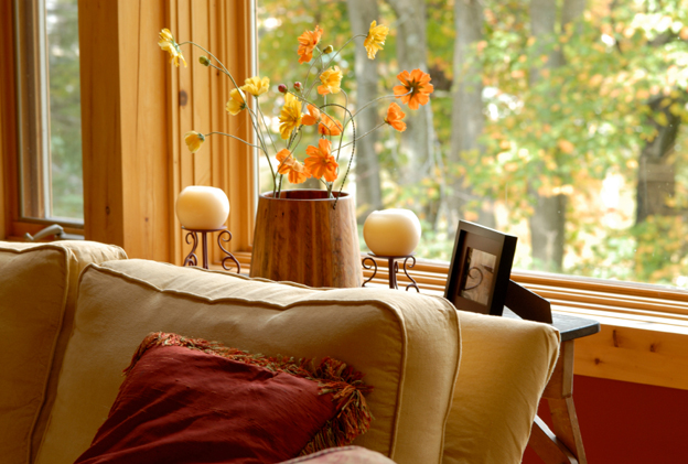 A couch near a window, with candles and flowers on a table in the background.